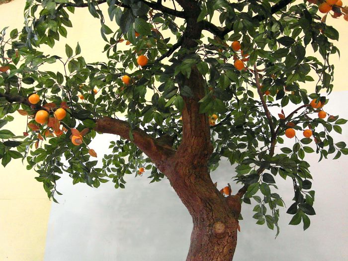 Künstlicher Mandarinenbaum mit grünen Blättern und gebogenem Stamm